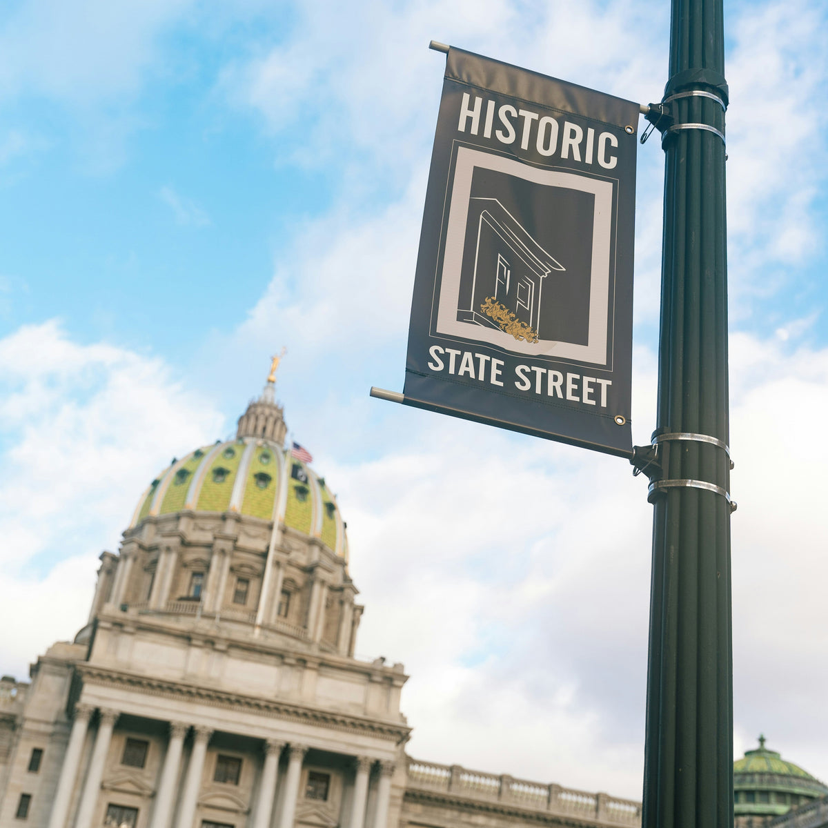 Historic State Street sign in front of a large building with a dome under a blue sky.
