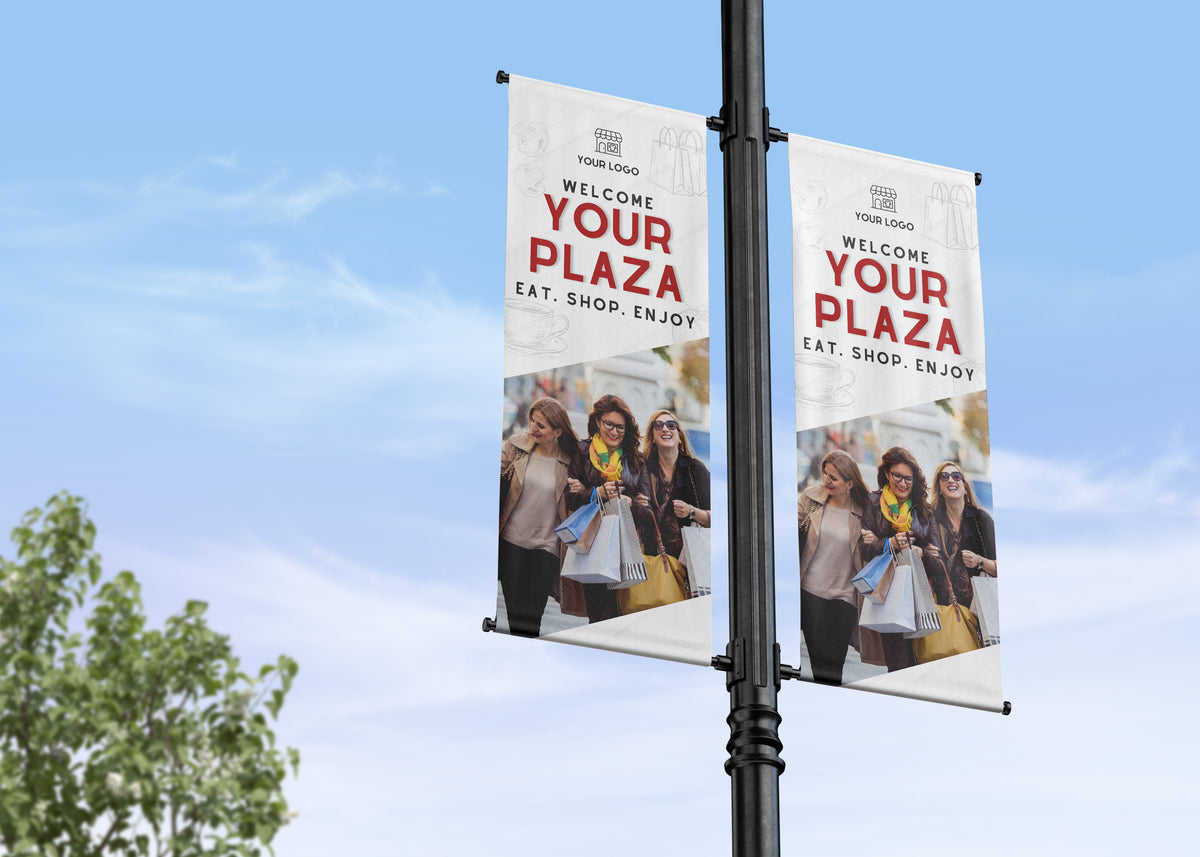 Two promotional banners on a street light pole with a clear blue sky background.