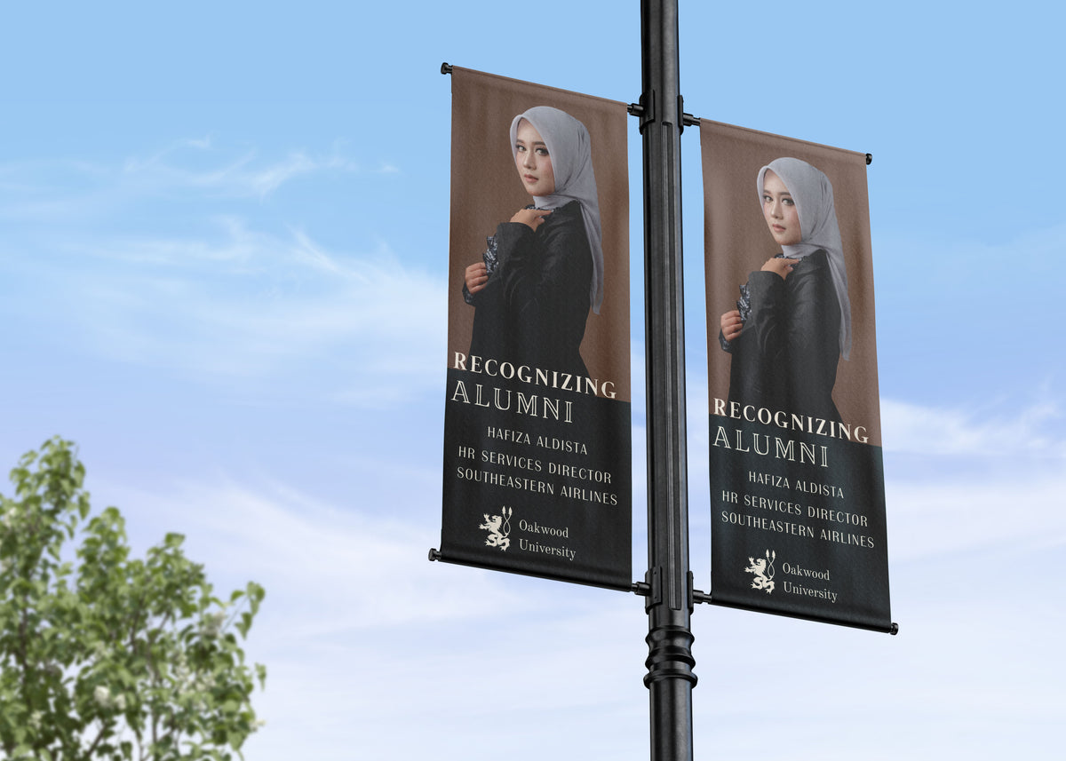 Two banners on a pole with a woman's portrait and text against a blue sky.