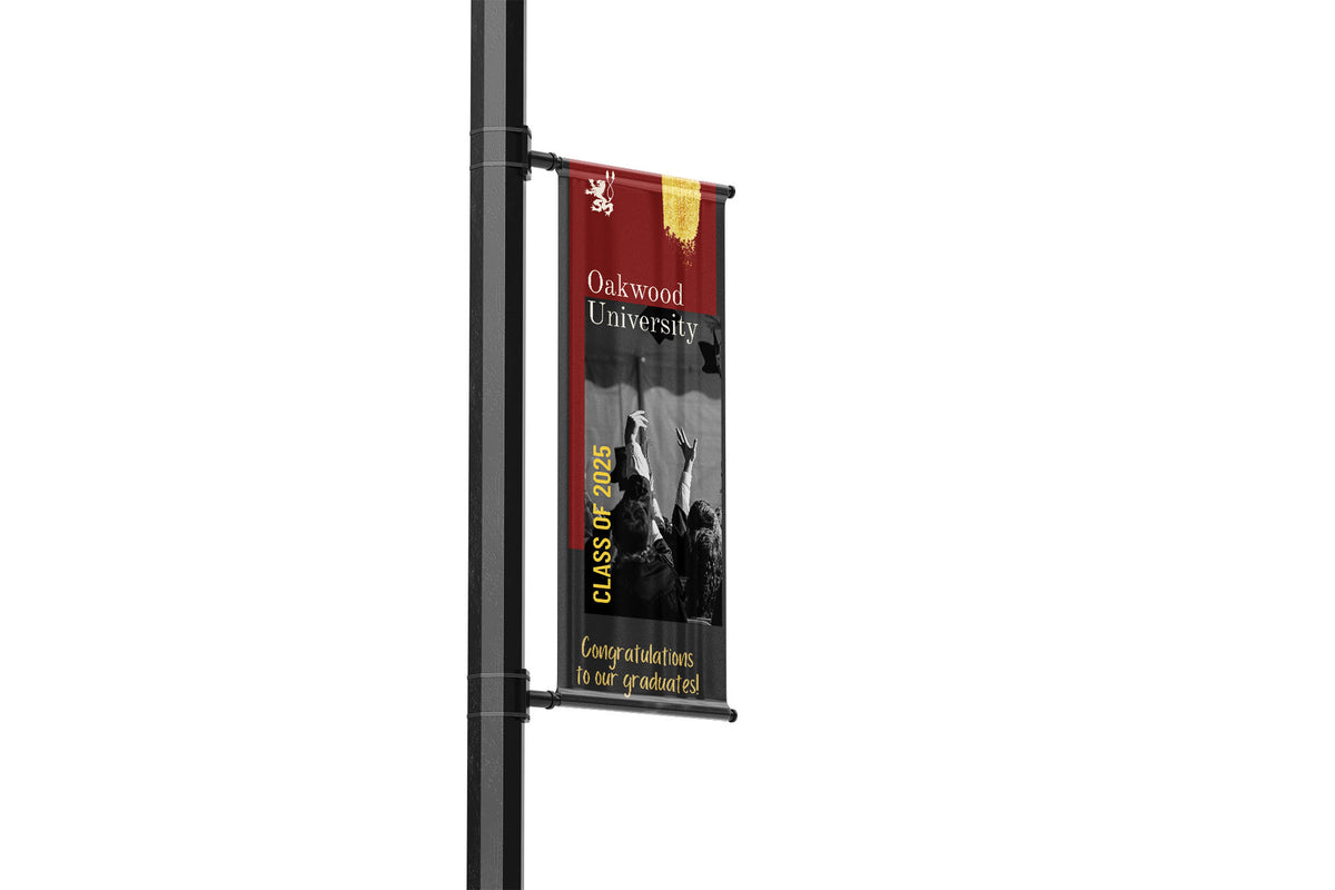 Banner with Oakwood University graduation banner on a light pole against a white background