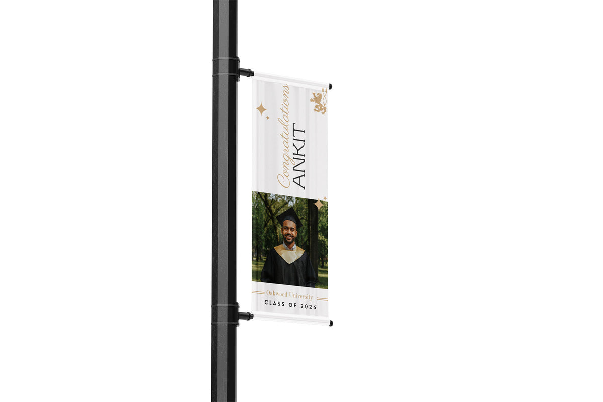 Street light pole with a graduation-themed banner featuring a photo of a person and text.
