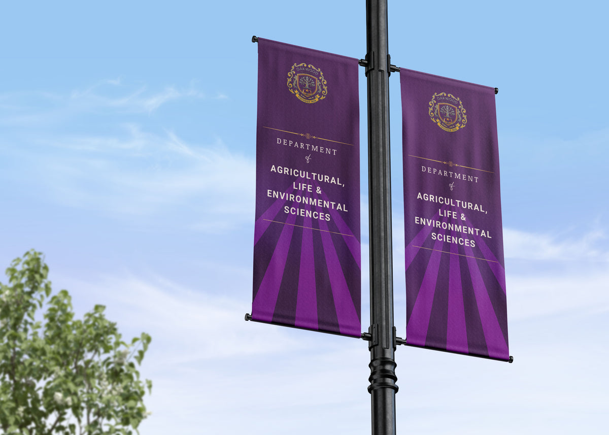Two department and faculty banners which are purple banners on a pole with text and logos against a blue sky.
